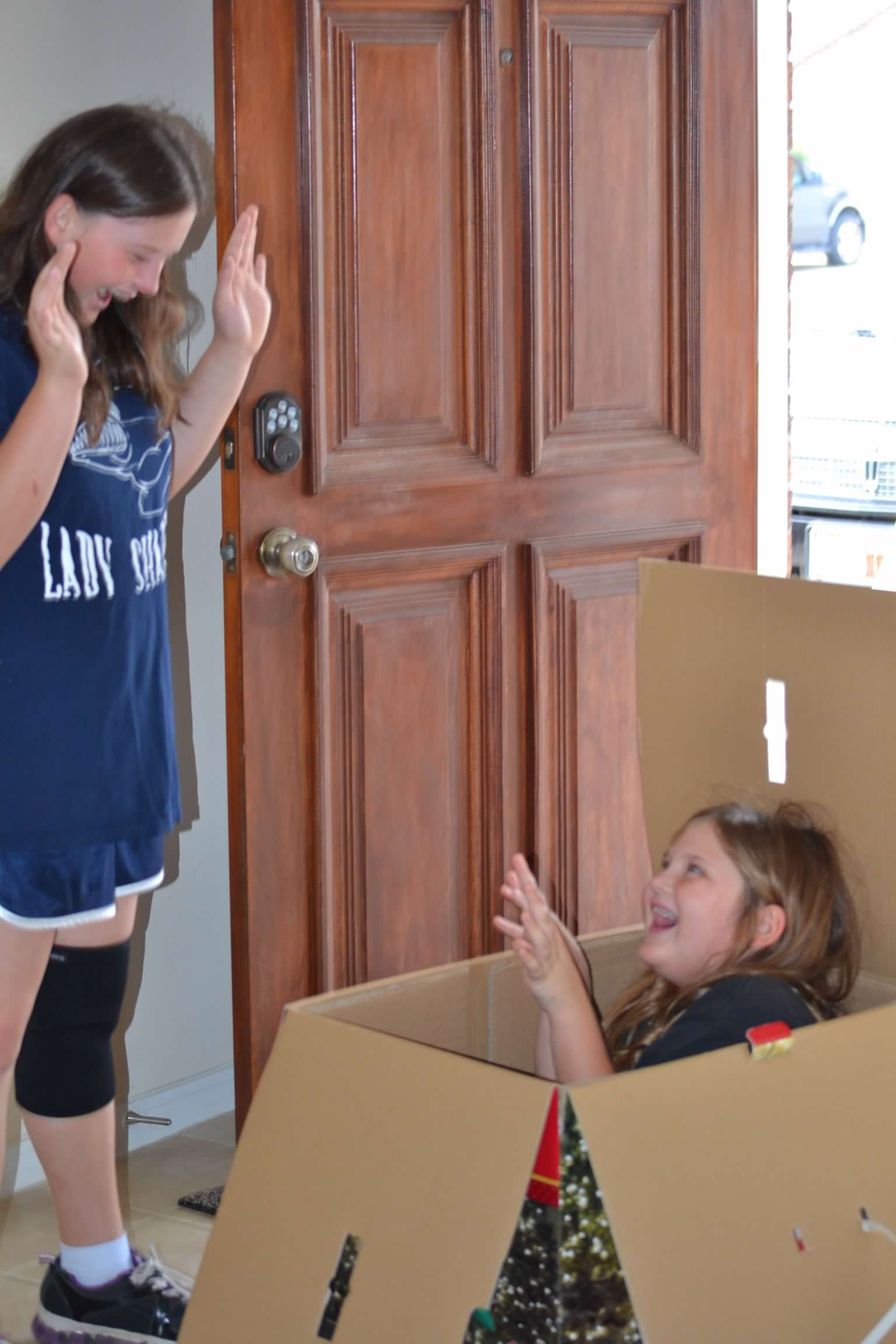 Bailey Schmitt laughing with her sibling around a cardboard fort