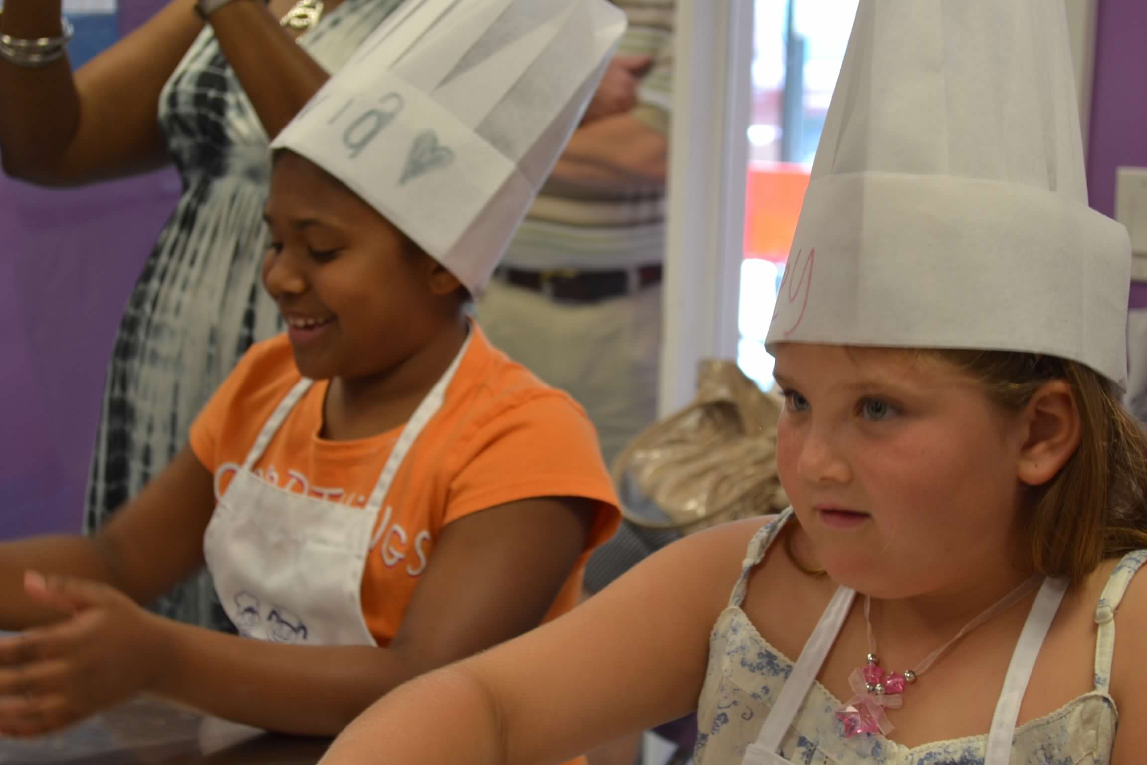 Bailey Schmitt as a young girl, wearing a paper chef hat at a cooking class