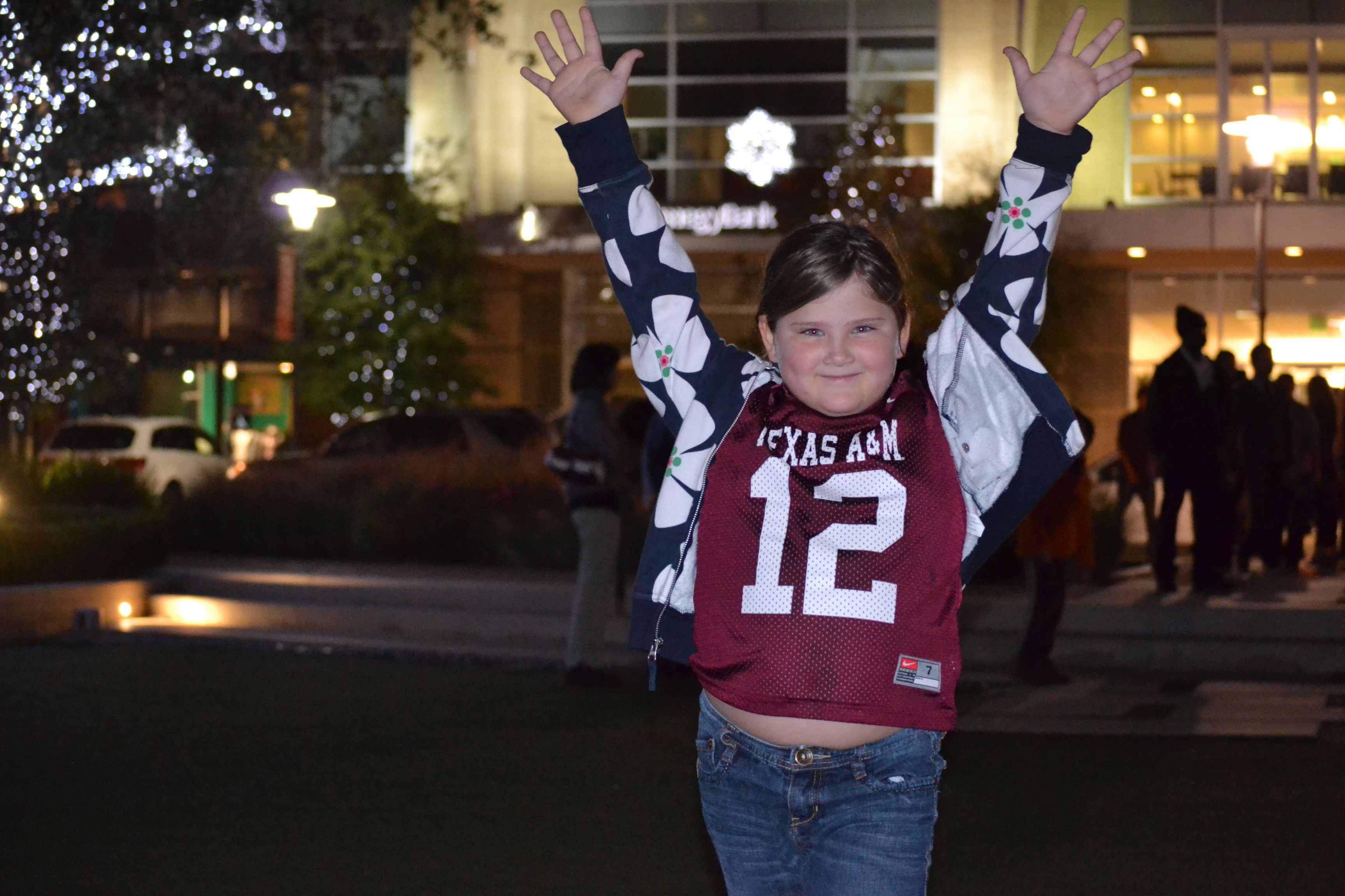 Bailey Schmitt, arms raised in celebration, wearing a Texas A&M jersey on an evening outing