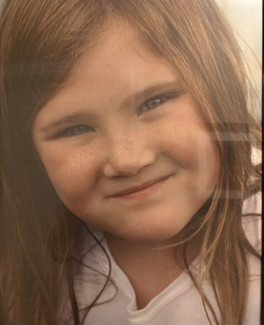 Close-up portrait of Bailey Schmitt smiling, with freckles across her cheeks