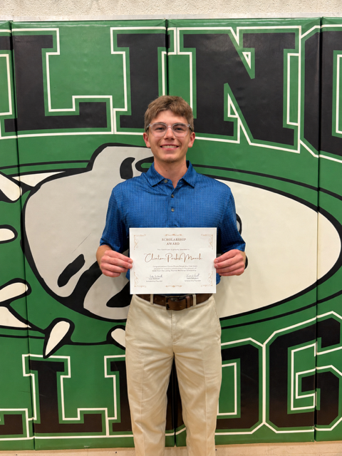 A Bailey Schmitt Memorial Fund scholarship recipient holding his certificate in front of the Bulldogs gym backdrop